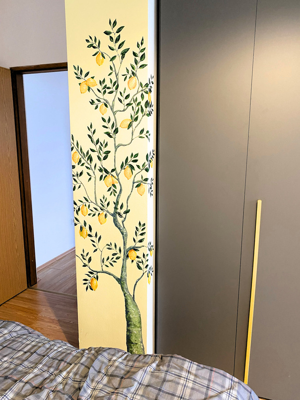 Photo of a wall with painted on it lemon tree as part of wall decoration of an apartment