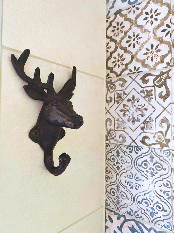 Interior design photo of a bathroom with deer-shaped hook for towels and Barcelona tiles