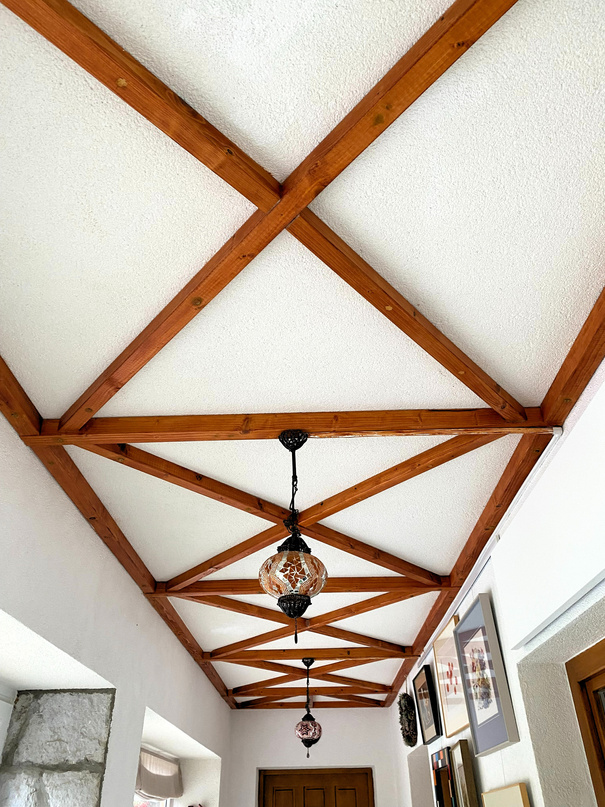 Photo of dark wood beams which are decorating the ceiling of the entrance zone of an country house